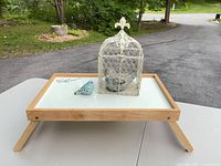 Tray, ceramic bird, metal birdcage displayed together on tabletop