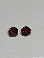 Front view of two round deep-red garnets on neutral background