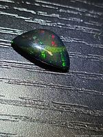 Triangular Ethiopian black opal showing multicolored flashes