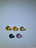 Five pear-cut sapphires arranged on white background