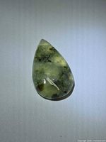Front view of pear cabochon prehnite showing color and inclusions