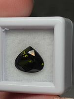 Faceted forest green pear tourmaline in gem jar close-up