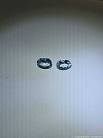 Pair of pale blue oval aquamarines on neutral background