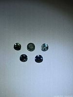 Five round multicolour sapphires under light