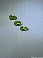 Three oval peridots displayed on neutral background