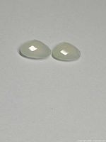 Pair of tea green chalcedony gemstones on neutral background