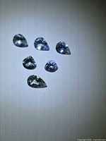Six pear-cut multicoloured Tanzanites displayed on neutral background