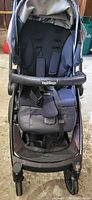 Front view of open stroller showing seat, harness, bumper bar and wheels