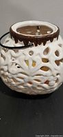 Angled close-up of lantern showing openwork pattern, brown rim, black metal handle