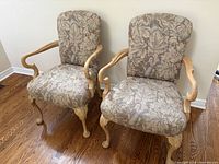 Front view of both upholstered armchairs showing fabric pattern and wood frame