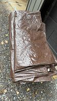 Folded brown polyethylene cover with frame poles visible