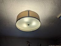 Complete view of light fixture mounted on ceiling showing drum shade and diffuser