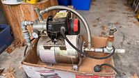 Pump mounted on small stainless tank inside box showing hoses and pressure gauge