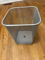 Overall view of silver mesh garbage can showing shape and condition
