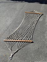 Full view of rope hammock laid flat showing spreader bars and metal ring