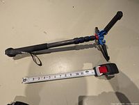 monopod collapsed with tripod feet extended beside 0-60 cm tape for scale