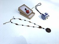Full lot showing necklace, ceramic cube ornament with cord, apple ornament in box