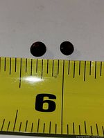 Two round faceted red garnets with measuring tape showing scale