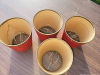 Interior view of four red felt lamp shades showing clip-on wire fittings and cream linings