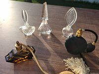 Group of five perfume bottles on table in sunlight