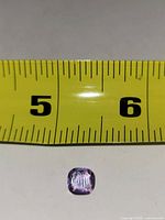 Top view of cushion-cut amethyst beside ruler showing ~6 mm width