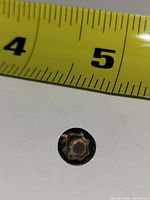 Top view of faceted round smoky topaz next to tape measure showing ~11 mm diameter