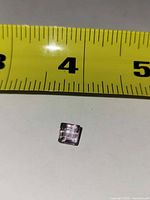 Front view of square faceted light amethyst next to ruler showing size ~4 mm