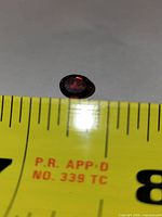 oval red garnet on measuring tape showing size about 6-7 mm
