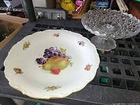Porcelain fruit charger and clear pressed glass pedestal dish side by side