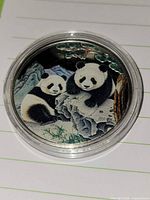 Front of silver medallion showing two pandas with enamel coloring