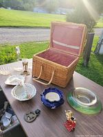 Overall view of basket and assorted glass, ceramic and metal pieces on table