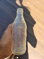 Close-up of bottle held in hand showing diamond panel and embossed details