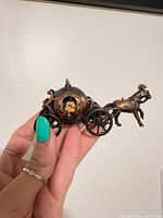 Side view of miniature bronze carriage with horse showing overall design