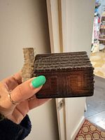 Front view of brown glass log cabin perfume bottle with gray chimney stopper