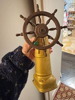 Front view of painted metal ship wheel on gold pedestal