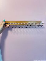 Entire tie rack held against wall showing wood rail and metal hooks