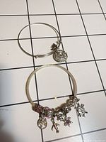 Both bracelets laid flat showing all charms