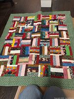 Full view of multicolor log cabin quilt with green border