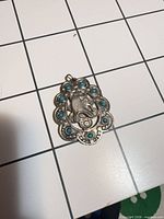 Front view of pendant showing pharaoh motif and turquoise cabochons