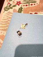Maple leaf charm and cube bead on blue surface