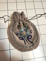 Full view of taupe velvet pouch with beaded design and drawstring