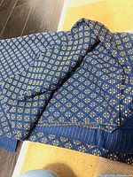 Overall view of folded navy fabric showing geometric pattern and selvage