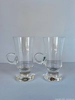 Front view of both clear pedestal Spanish coffee glasses showing handles and bases