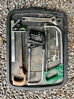Tray displaying six hand tools: panel saw, two hacksaws, combination square, adjustable wrench, angle gauge