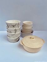 Stacks of marble-swirl and beige ramekins beside cheese baker with lid