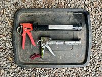 Top-down view of two caulking guns on tray