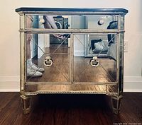 Front view of one mirrored glass side table showing drawer, cabinet doors, ring pulls