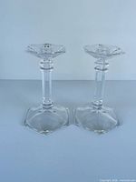 Front view of both clear glass candlesticks standing upright
