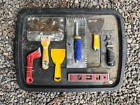 Group of seven finishing and painting hand tools laid on black tray