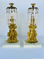 Full view of both gilt figural candlesticks with prisms and marble bases